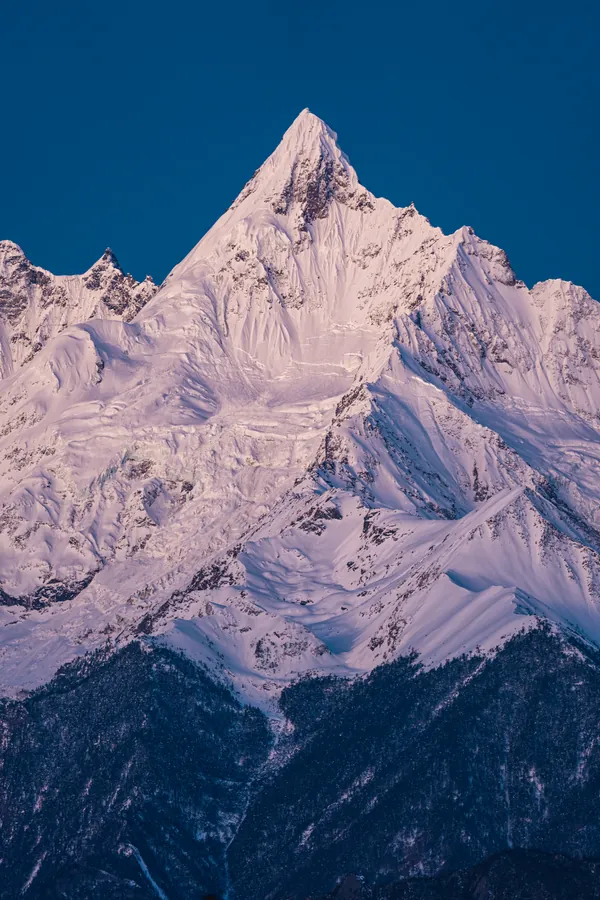 粉紫色雪峰在深蓝天空下耸立,冰雪纹理向暗色山脚延伸。